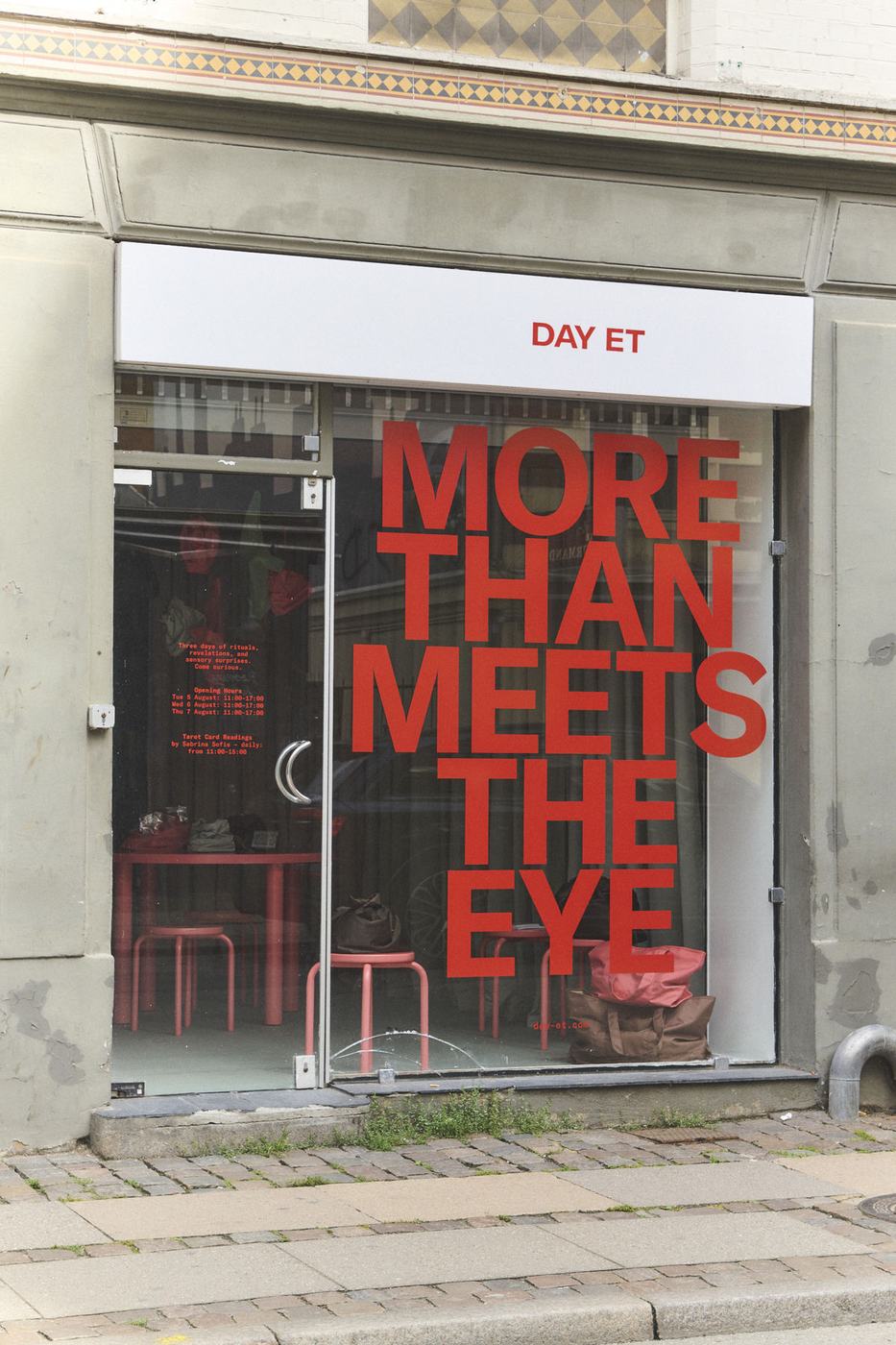 Storefront window with large red vinyl type reading MORE THAN MEETS THE EYE