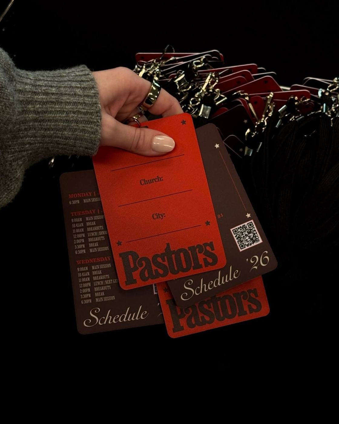 Red and brown printed lanyard schedule cards held in a hand